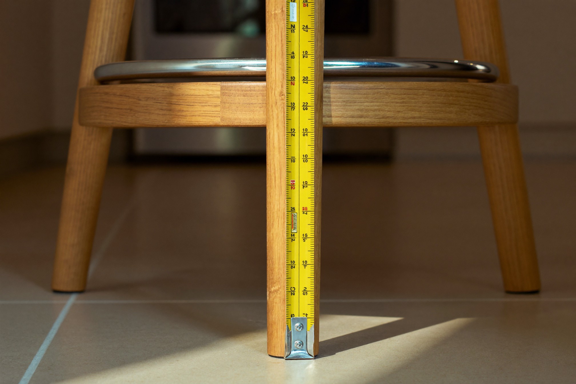 Taśma miernicza przyłożona pionowo od podłogi do siedziska hokera counter-height — pomiar wysokości siedziska