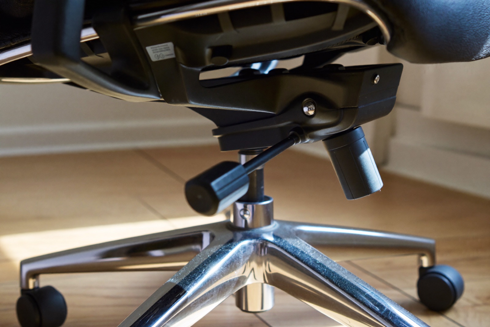 Spód krzesła biurowego: mechanizm synchro, siłownik gazowy, metalowy krzyżak i kółka