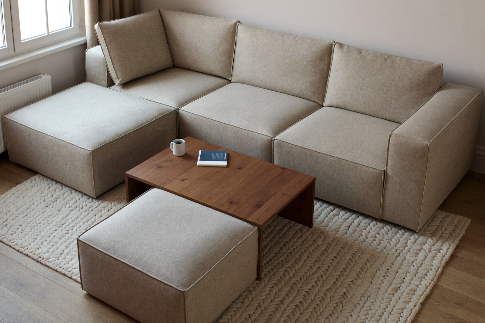 Sofa modułowa ustawiona w literę U wokół niskiego stolika w kwadratowym salonie
